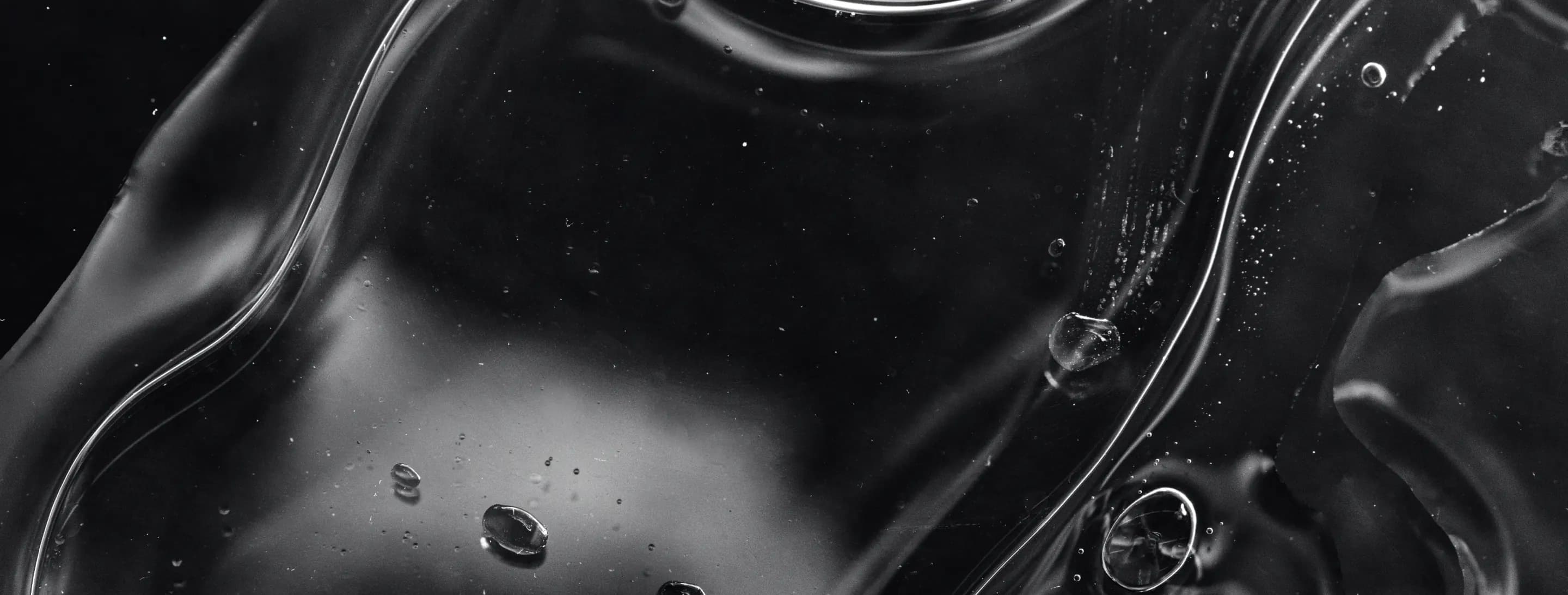 Dark liquid surface with bubbles, close up
